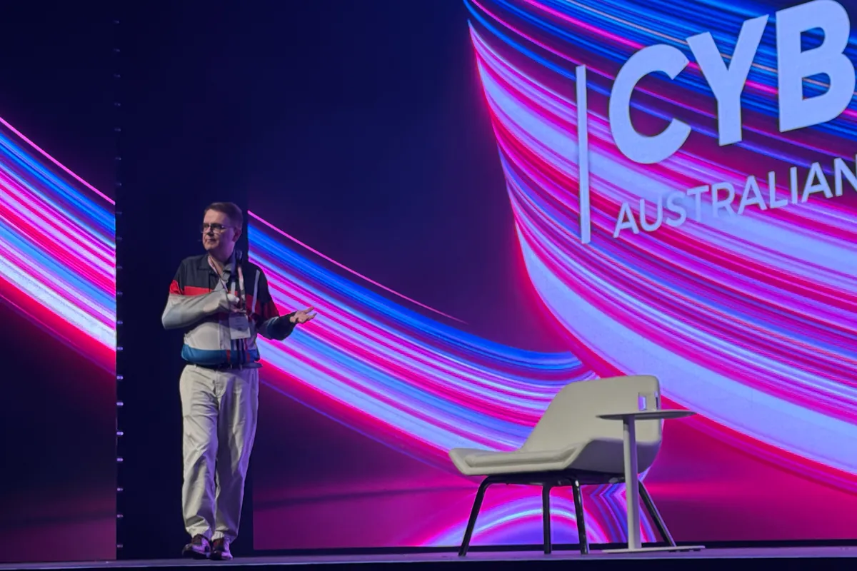 Mark Vos presenting on the main plenary stage at CyberCon 2026 in Melbourne, with the Australian Cyber Conference branding on the screen behind him